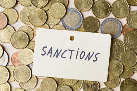 Label with word Sanctions on background of Euro coinsの写真素材