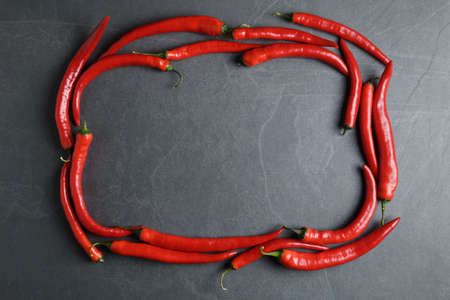 Hot red peppers arranged in a frame on gray stone backgroundの写真素材