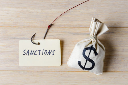 Table with the word "sanctions" next to the sack of money with USD symbol. Ð¡oncept of economic and political problemsの写真素材