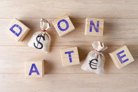 Money bags with dollar and Euro symbols and wooden cubes with letters DONATEの写真素材