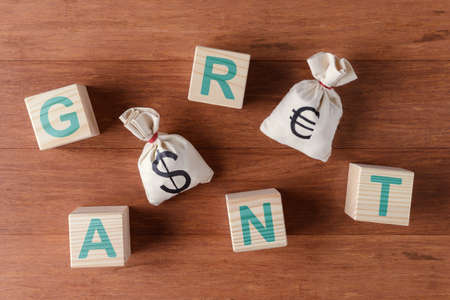 Money bags with dollar and Euro symbols and wooden cubes with letters GRANTの写真素材