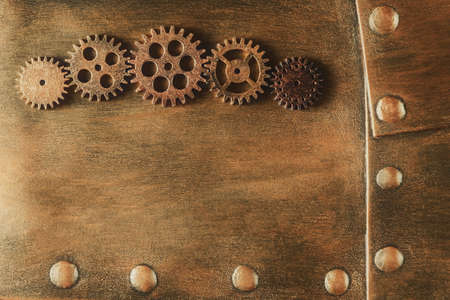 Gears on aged metal plates with rivets. Steampunk background with copy spaceの写真素材