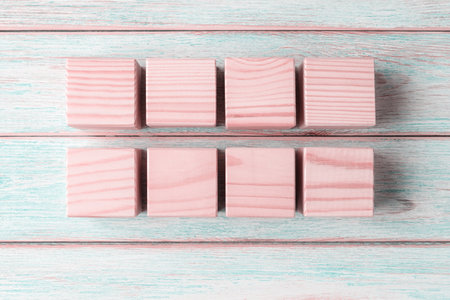 Eight blank pink wooden cubes on wooden platesの写真素材