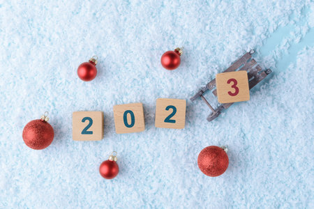 Christmas snowy background with Xmas decoration and wooden blocks with number 2023の写真素材