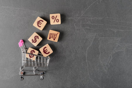 Shopping cart with Euro, USD, percentage and cart symbols on wooden cubes. Shopping and credit conceptの写真素材