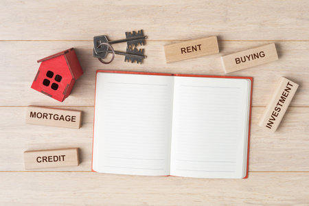 Open blank notebook and house model on wooden background. House buying and mortgage conceptの写真素材