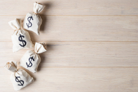 Money bags with USD symbols on light wooden background with copy spaceの写真素材