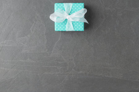 Blue gift box on grey stone background with copy spaceの写真素材