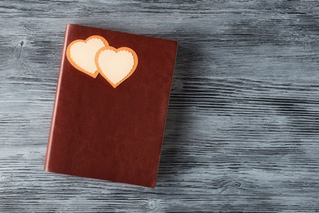 Brown notebook with two Valentines hearts on aged wooden background with copy space. Valentineâs day greetingの写真素材