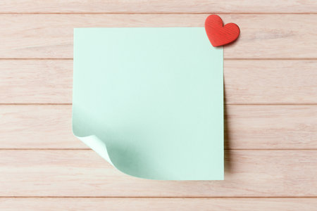 Blank sticky note with copy space and red heart on wooden background. Valentines day greeting conceptの写真素材