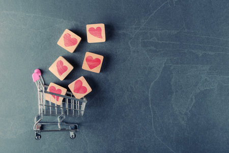 Shopping cart with Valentines hearts on wooden blocks. Valentineâs day conceptual greetingの写真素材