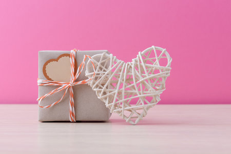 Craft handmade gift box and valentineâs heart over pink background with copy space. Valentineâs day conceptual greetingの写真素材