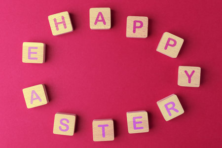 Wooden blocks arranged in egg shape with lettering Happy Easter on viva magenta background. Easter...
