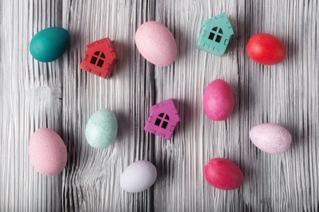 Top view of painted Easter eggs and decorative houses on rustic wooden background. Easter holiday conceptの写真素材