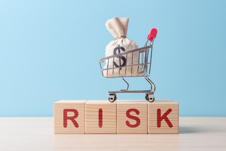 Money bag with dollar sign in shopping cart on wooden cubes with caption RISK. Currency risk conceptの写真素材