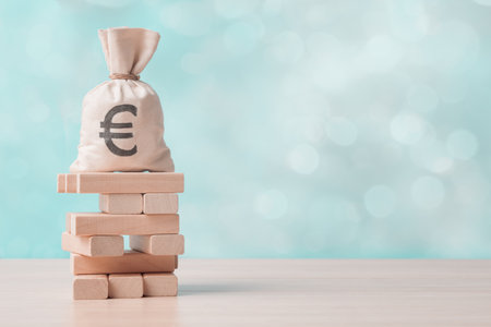 Money bag with Euro sign on wooden block tower over abstract background with copy space. Business risk and financial instability concept.の写真素材