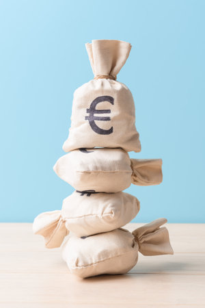 Pile of money bags with Euro symbols over blue backgroundの写真素材