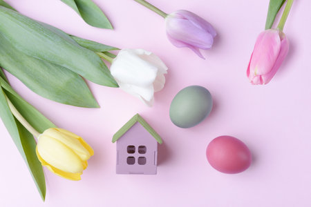 Easter eggs, tulip flowers and decorative house. Easter holiday greeting concept