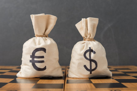 Money bags with Euro and Dollar signs on chessboard. Currency competition concept between Euro and US Dollarの写真素材
