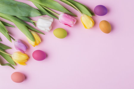 Tulip flowers and decorative Easter eggs on pink blank paper background with copy spaceの写真素材