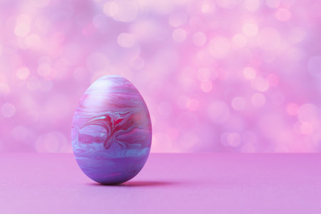 Decorative painted Easter egg against abstract background with copy space. Trendy Easter holiday greeting conceptの写真素材