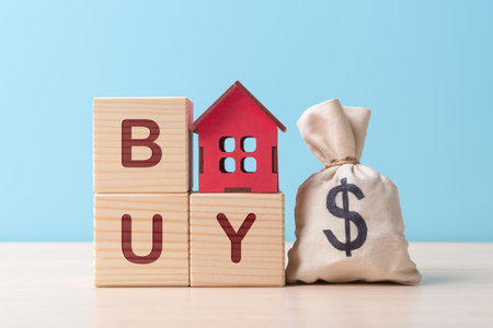 Moneybag with Euro symbol and wooden house model on blocks with letters Buy. Mortgage and house buying conceptの写真素材