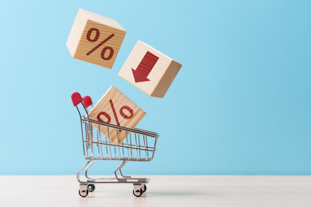 Shopping cart with cubes falling into it with percent symbols and down arrow. Concept of discount or sale in a storeの写真素材