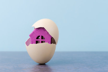 Pink House in egg shell on blue background with copy space. Conceptual Easter greeting cardの写真素材