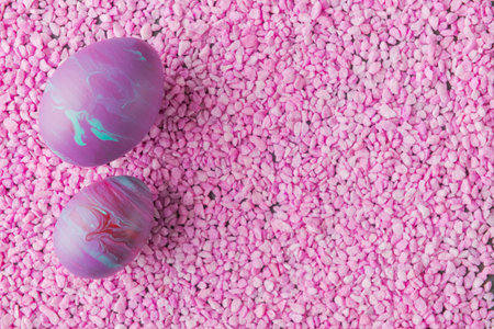 Painted Easter eggs on pink stone background with copy space. Trendy fluid art decorationの写真素材