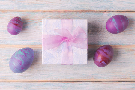 Decorative Easter eggs and gift box on wooden background. Trendy fluid art decoration. Easter holiday conceptの写真素材