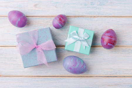 Easter eggs and gift boxes on wooden background with copy space. Trendy fluid art decoration. Easter holiday conceptの写真素材