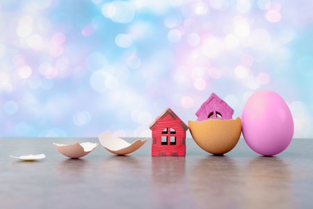 Tiny houses in eggs shell against abstract holiday background with copy space. Conceptual Easter greeting cardの写真素材