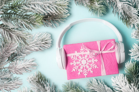 Pink gift box with headphones and frosty Christmas tree branches. New Year and Xmas greeting ideaの写真素材
