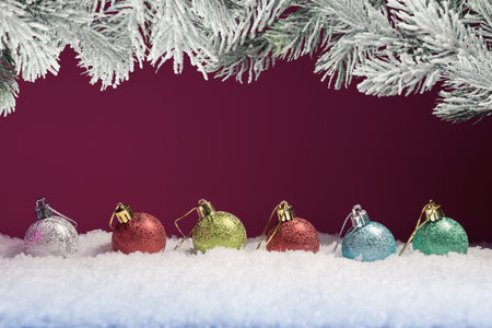 Christmas balls in snow and frosty fir tree branches against pink background with copy space. New Year and Xmas greetingの写真素材