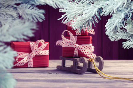 Red gift boxes on Santaâs sleigh framed by frosty Christmas tree branches. New Year and Xmas greeting cardの写真素材