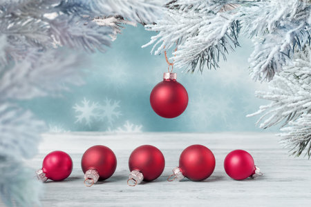 Red Christmas balls on frosty fir tree twig over abstract defocused holiday lights. Christmas and New Year greeting conceptの写真素材