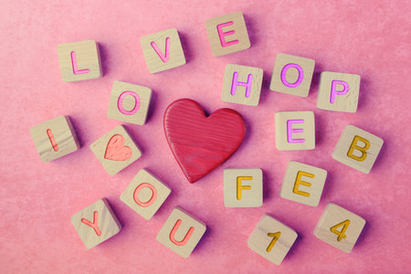 Wooden blocks with inscribed letters and a red heart on a pink background. Conveys messages of love and affection. Valentine's day greeting conceptの写真素材