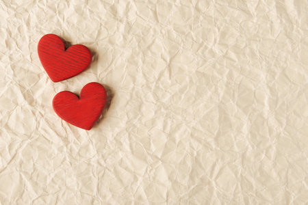 Close-up of two red hearts placed on a textured crumpled paper, symbolizing love, affection, and Valentineâs Dayの写真素材