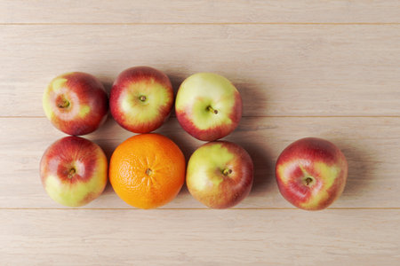 A creative representation of apples and oranges on a wooden table partially obscured by a blurred...
