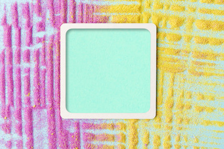A square frame with a white border and copy space on background with yellow and pink sandの写真素材
