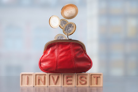 Financial growth and investment strategy represented by a red coin purse in wooden blocks spelling INVEST and walling into purse Euro coins.の写真素材