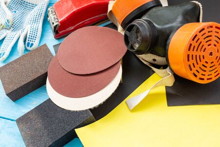 Abrasives, sanding paper, sponges and wheel, respirator on the blue wooden background close upの写真素材