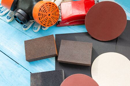 Abrasives, sanding paper, sponges and wheel, respirator on the blue wooden background close upの写真素材