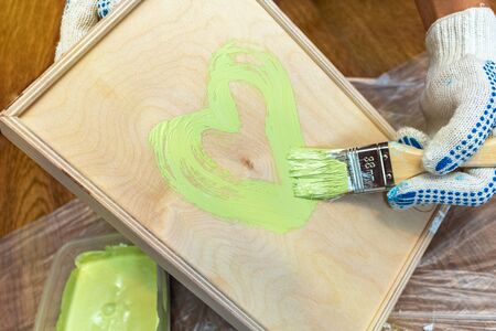Painting a wooden tray in a green khaki color with a tassel paintbrush close-up on the backgroundの写真素材