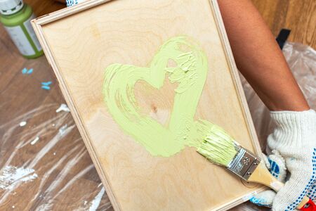 Painting a wooden tray in a green khaki color with a tassel paintbrush close-up on the backgroundの写真素材