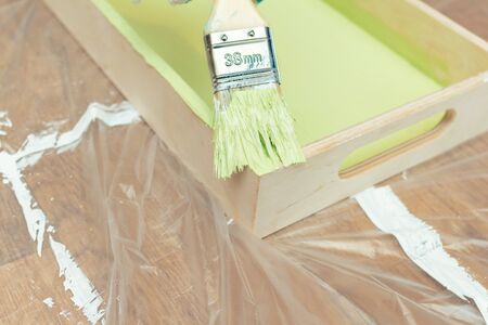 Painting a wooden tray in a green khaki color with a tassel paintbrush close-up on the backgroundの写真素材