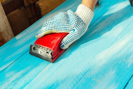 Sanding with Abrasives in a hand sanding paper sponges wooden painted blue wooden table background close upの写真素材