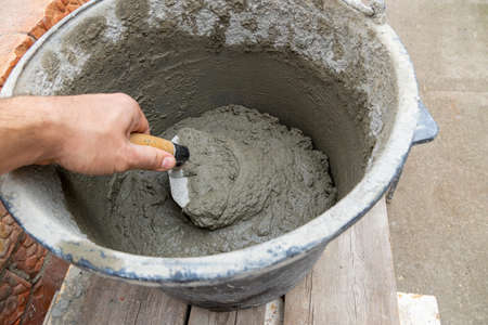 Cement-sand concrete mix in a plastic bucket with a trowel