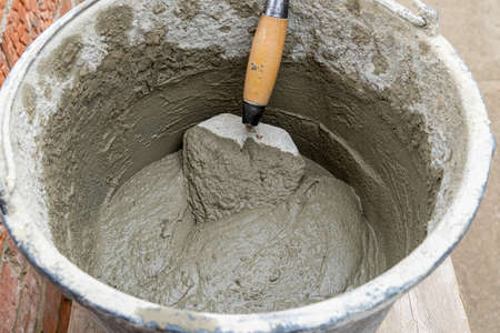 Cement-sand concrete mix in a plastic bucket with a trowelの写真素材