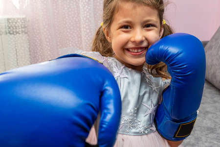 Little girl wearing blue boxing gloves and a holiday dress with starsの写真素材